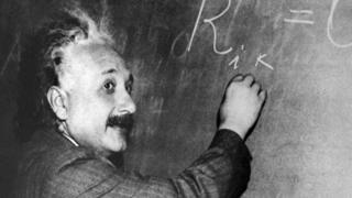 Albert Einstein writing on a blackboard