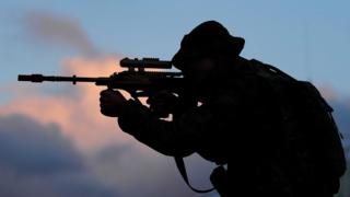 The silhouette of a soldier aiming a gun