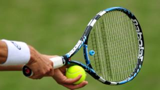 A generic shot of a tennis player about to serve a tennis ball with a tennis racket.