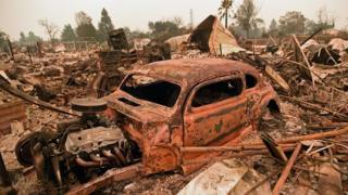 A destroyed car is seen among the ruins of a burned neighborhood after the Carr fire passed through the area of Lake Keswick Estates near Redding, California on July 28, 2018