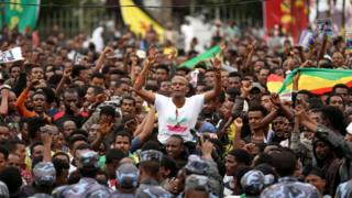 Protestors gesture in front of federal police officers during a protest following the burial ceremony of Simegnew Bekele, Ethiopia's Grand Renaissance Dam project manager