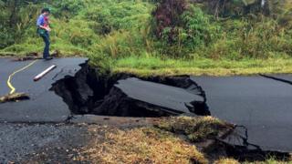 A geologist inspects cracks on a road in Leilani Estates, following eruption of Kilauea volcano, Hawaii on 17 May 2018.