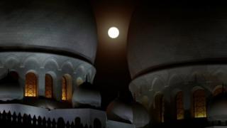 rises behind the Sheikh Zayed Grand Mosque in Abu Dhabi