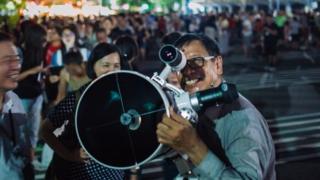 People set up telescopes to witness a rare lunar eclipse near 27 in Taipei, Taiwan