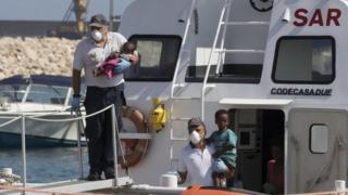 Children are brought ashore on an Italian coast guard boat at Pozzallo, Sicily, 15 July 2018