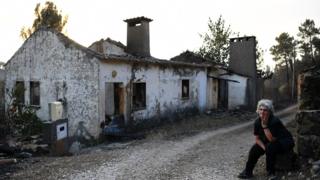 Maria Manuela Mendes sits beside her burnt house in Mendeira, near Cernache do Bonjardin, on June 19, 2017