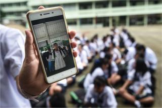 A Thai student shows a picture of missing classmate Prachak Sutham