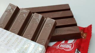 Two similar-looking chocolate bars are arrayed on a table - one embossed with a stork, the other with the Kit Kat logo