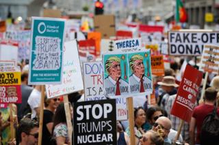 Protesters against the UK visit of US President Donald Trump gather with placards to take part in a march and rally in London