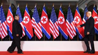 US President Donald Trump (R) and North Korea's leader Kim Jong Un (L) walk toward one another at the start of their historic US-North Korea summit, at the Capella Hotel on Sentosa island in Singapore on 12 June 2018.
