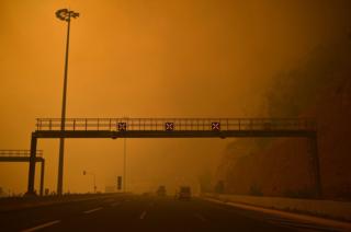 A road block is set up amid smoke as a wildfire burns in Kineta, near Athens, on July 23, 2018