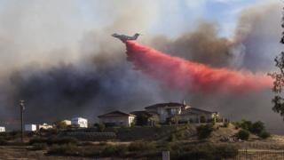 A plane drops fire retardant near a home to stop the wind driven Liberty Fire near Los Alamos Road on 7 December 2017 in Murrieta, California