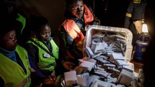An election official opens a ballot box during the tally of the votes at a polling station for the general election in the suburb of Mbare of Zimbabwe