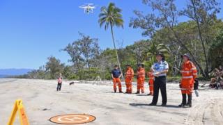 Australian police and emergency workers fly a drone during search efforts on a beach in Queensland
