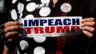 A protester holds a sign calling for the impeachment of US president Donald Trump during a rally and press conference at San Francisco City Hall