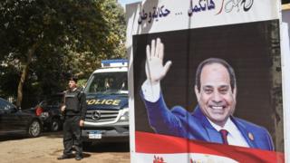 Egyptian policemen standing next to an electoral banner depicting President Abdel Fattah al-Sisi in the capital Cairo. March 26, 2018