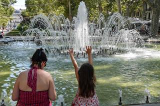 A woman and child cool down at a fountain in Montpellier