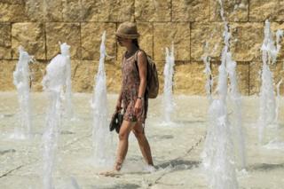 A woman cools herself in a fountain near the Ara Pacis monument, in central Rome