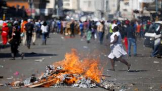 Locals run as supporters of the opposition Movement for Democratic Change (MDC) party of Nelson Chamisa burn barricades in Harare, Zimbabwe, 1 August 2018