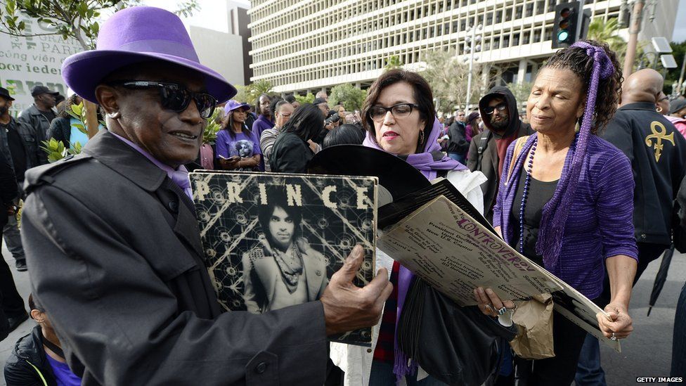 Prince fans hold his records at a memorial