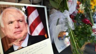 A photo of John McCain sits with flowers outside the late senator's Phoenix office.
