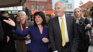 Julia Banks and Malcolm Turnbull walk and gesture in front of reporters