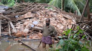 Ajith Prasad stands in front of the rubble of his house on the outskirts of Kozhikode