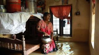 An Indian woman sits inside her house immersed in flood waters in the Ernakulam district of Kochi