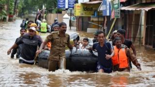 Rescuers with a rubber boat wade through waist-deep floodwaters in Aluva in the south Indian state of Kerala