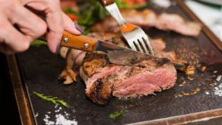 A person cutting up a steak