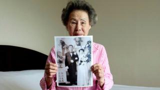 Lee Chun-ja, 88, holds up an old picture of her wedding in a hotel room (19 Aug 2018)
