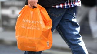 A man holding a Sainsbury's bag
