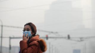 A woman wearing a face mask makes her way along a street in Beijing