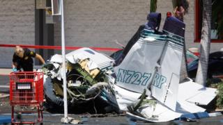 An investigator looks over the wreckage of a small plane that crashed into a strip mall parking lot in Santa Ana