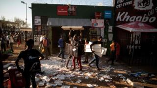 Looters take items from a foreign-owned shop in Soweto, Johannesburg, on August 29, 2018