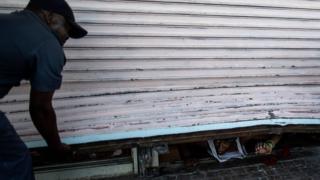 A suspected looter emerges from of a looted foreign-owned shop in Soweto to be detained by South African police officers in Johannesburg
