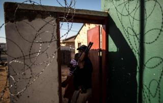 A South African police officer stands in the door way of a looted foreign-owned shop in Soweto,