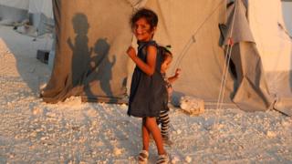 A displaced Syrian girl stands next to a tent provided by a Turkish humanitarian organisation at a camp for displaced people in northern Idlib province, 29 August 2018