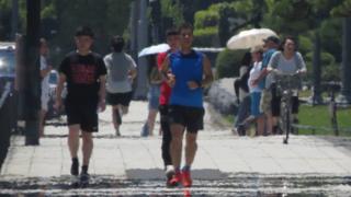 The effects of heat haze are seen as pedestrians walk along a street during a heatwave in Tokyo on August 2, 2018