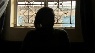 Woman in Kenya silhouetted against window