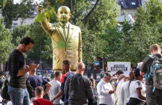 Bystanders look at a gold statue of Turkish President Recep Tayyip Erdogan in the city of Wiesbaden's Square of German Unity