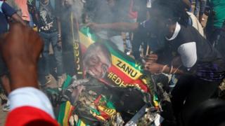 Supporters of the opposition Movement for Democratic Change party (MDC) burn an election banner with the face of Zimbabwe President Emmerson Mnangagwa in Harare, August 1, 2018