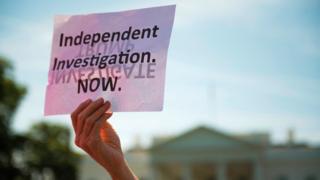 This file photo taken on May 10, 2017 shows a protester holding a placard in front of the White House during a protest demanding an independent investigation in the Trump/Russia ties after the firing of FBI Director James Comey in Washington, DC