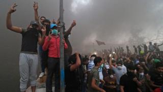 Protesters pose amid smoke near a burning building in Basra, 6 September 2018