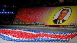 Performers holding up coloured boards creating a huge portrait of Kim Il-sung