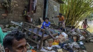 Sandhya Biji and her son in front of their damaged house on the banks of Pamba river in Mumndancava village after a flood on August 23, 2018 in Kerala, India