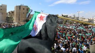 Syrian protesters wave their national flag as they demonstrate against the regime and its ally Russia, in the rebel-held city of Idlib on September 7, 2018