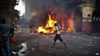A supporter of the Muslim Brotherhood runs past a burning vehicle during clashes with security officers close to Cairo's Ramses Square (16 August 2013)