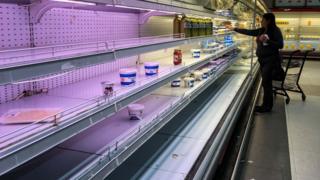 A customer looks for dairy products left in a shelf in a supermarket in Caracas, Venezuela on 27 August 2018