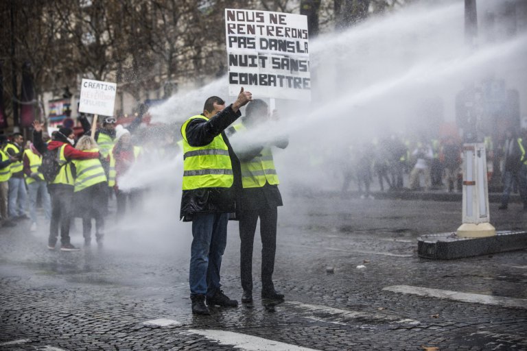 epaselect epa07186253 Protesters wearing yellow vests, as a symbol of French driver's and citizen's protest against higher fuel prices, faces the police forces during clashes on the Champs Elysee as part of a nationwide protest in Paris, France, 24 November 2018. The so-called 'gilets jaunes' (yellow vests) protest movement, which has reportedly no political affiliation, is protesting over fuel prices. EPA/CHRISTOPHE PETIT TESSON